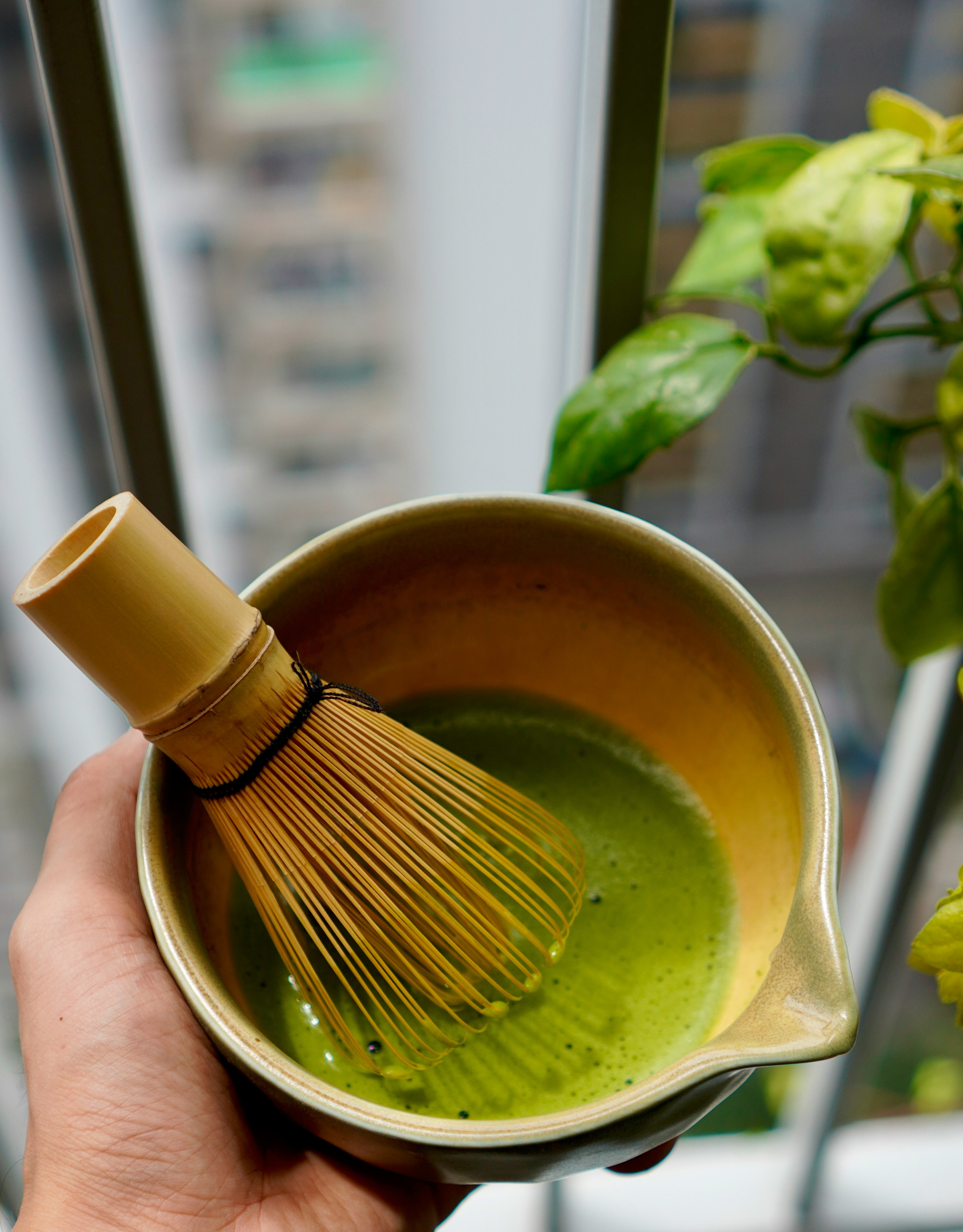 Freshly whisked ceremonial-grade Japanese matcha in a bowl with a bamboo whisk